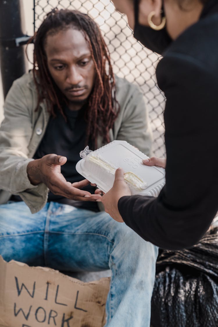 Woman Giving Food To The Man On The Street