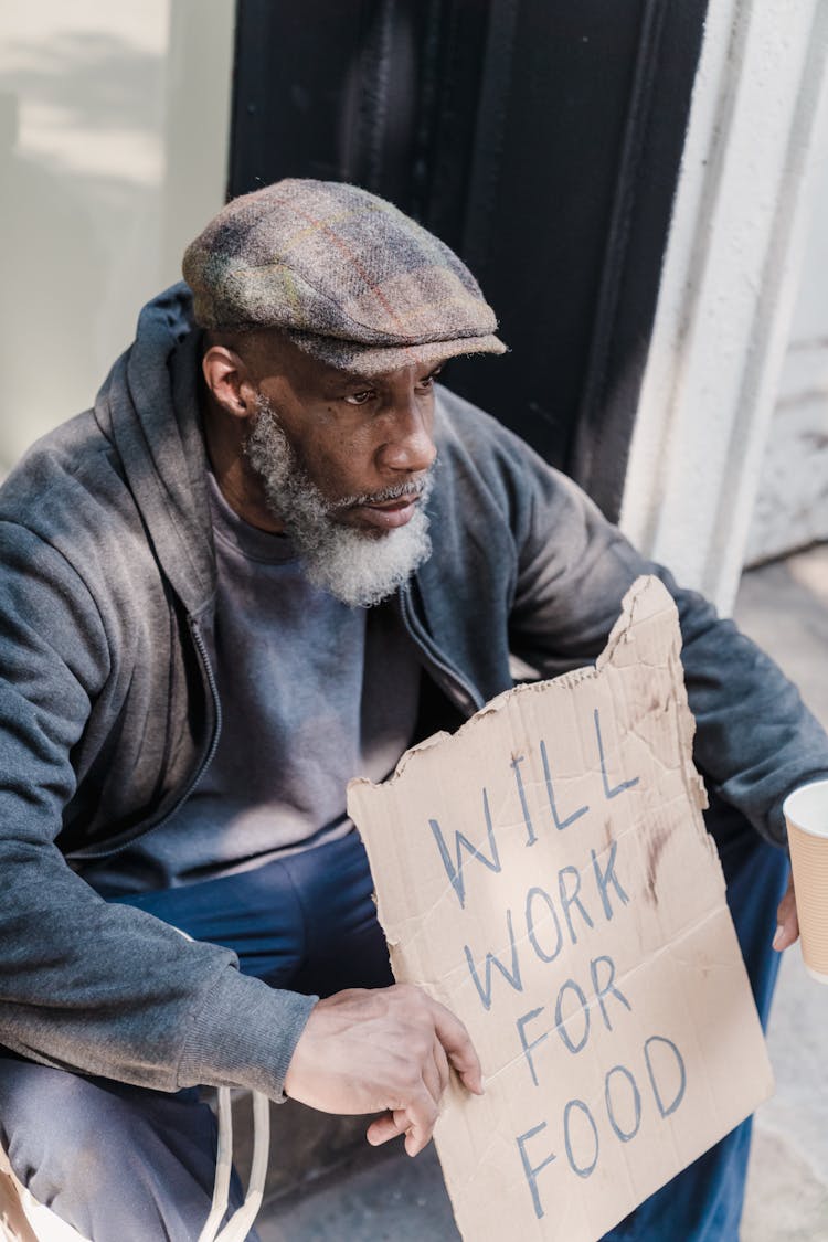 Man Sitting With Text On Cardboard