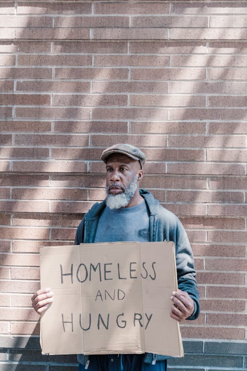 Photo of a Man Holding a Homeless and Hungry Cardboard Sign