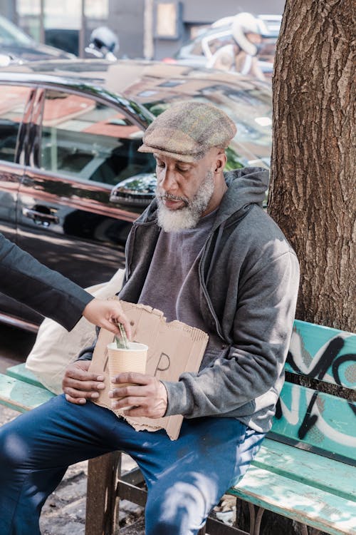 Photo of a Beggar Receiving Money from a Person