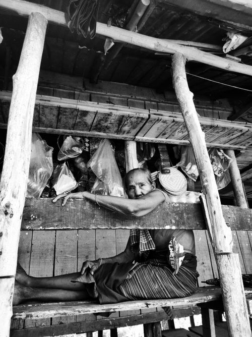 Free A captivating black and white portrait of a senior woman lounging in a rustic setting. Stock Photo