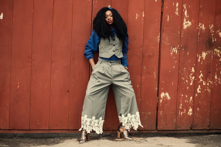 Woman In Blue And Grey Suit Leaning On Brown Wooden Wall