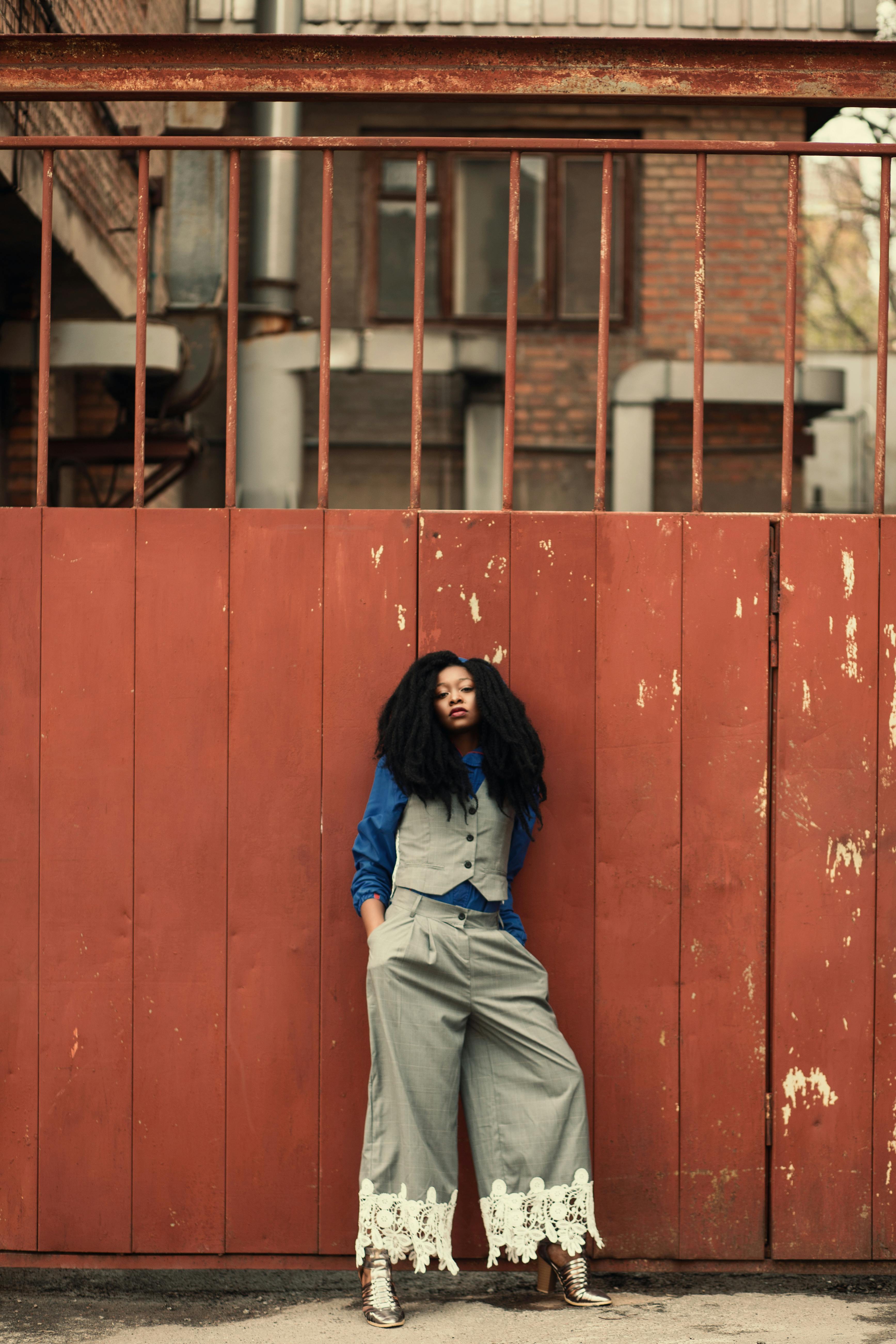 Woman Wearing Blue and Gray Outfit Standing Beside Gate · Free Stock Photo