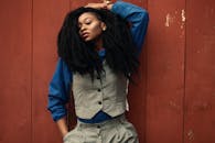 一位时尚女士自信地在质朴的红墙前摆出姿势