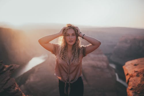 Free Woman in Brown Shirt Standing on Rock Formation Stock Photo