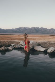 Serene scene of woman standing in lake with mountain view, perfect for relaxation themes.