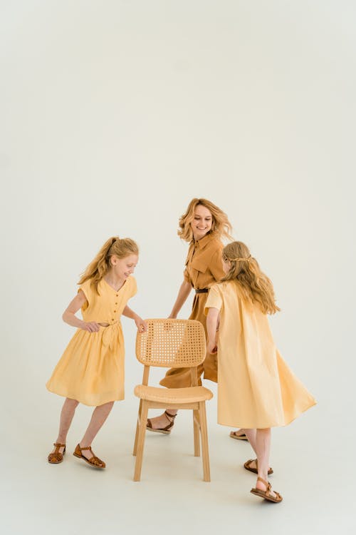 Free Woman and Girls Running Around a Chair Stock Photo