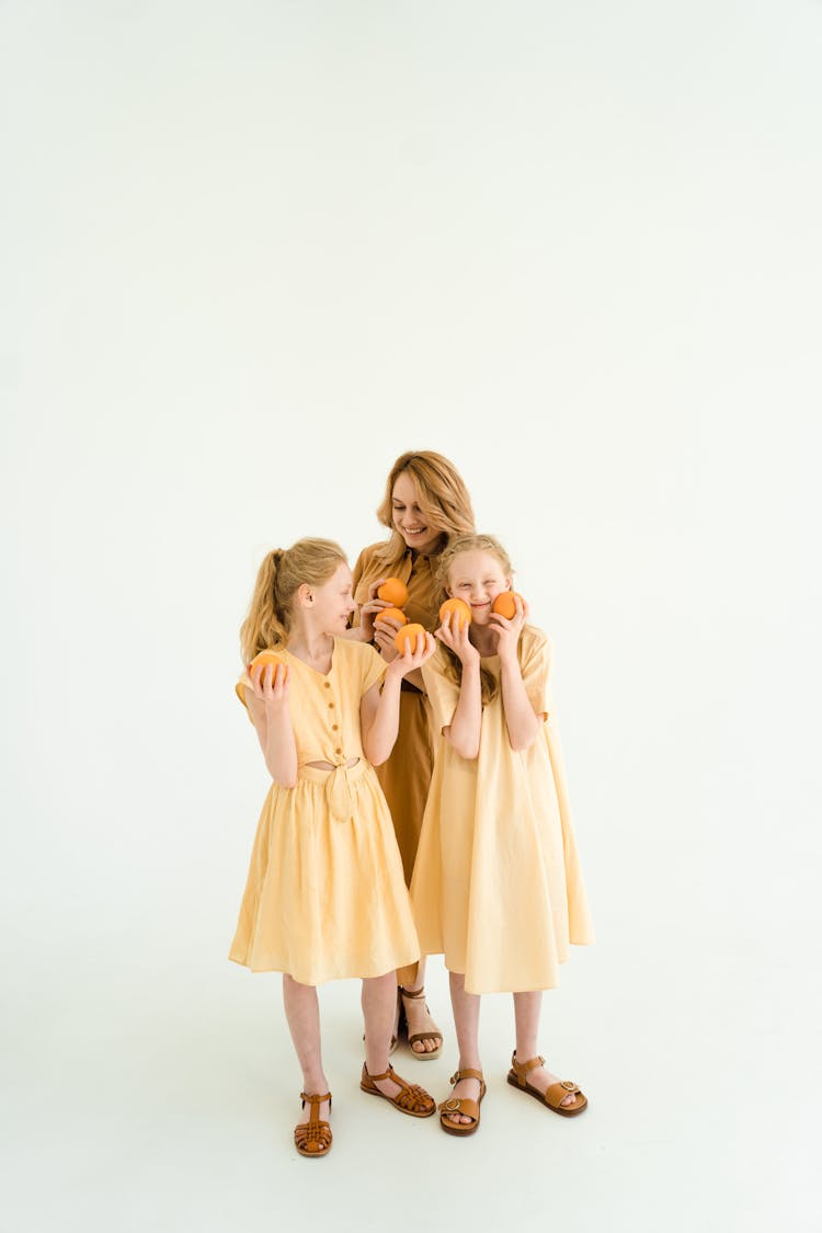 Woman And Two Girls Holding Fruits