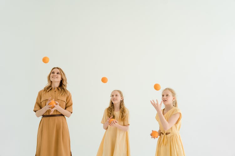 Family Playing With Orange Balls On White Background