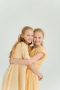 Two Young Girls Wearing Their Yellow Dresses on White Background