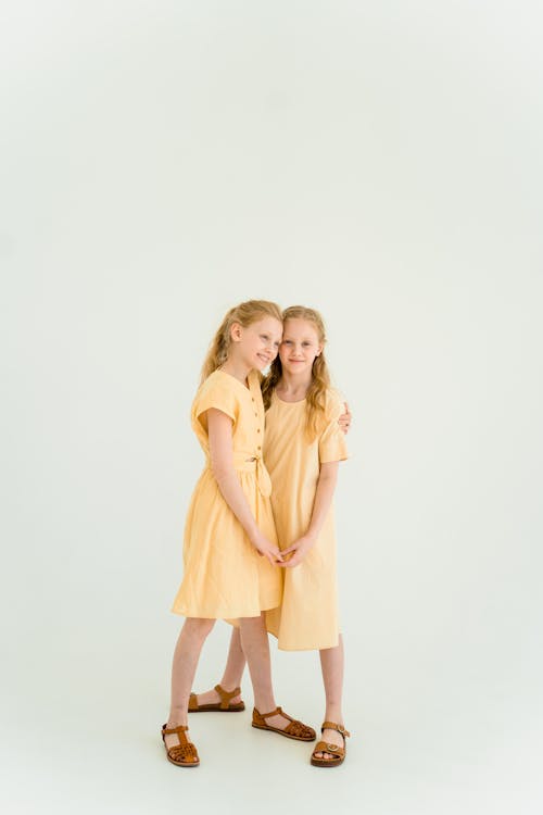 Two Young Girls in Yellow Dresses Standing Close to Each Other