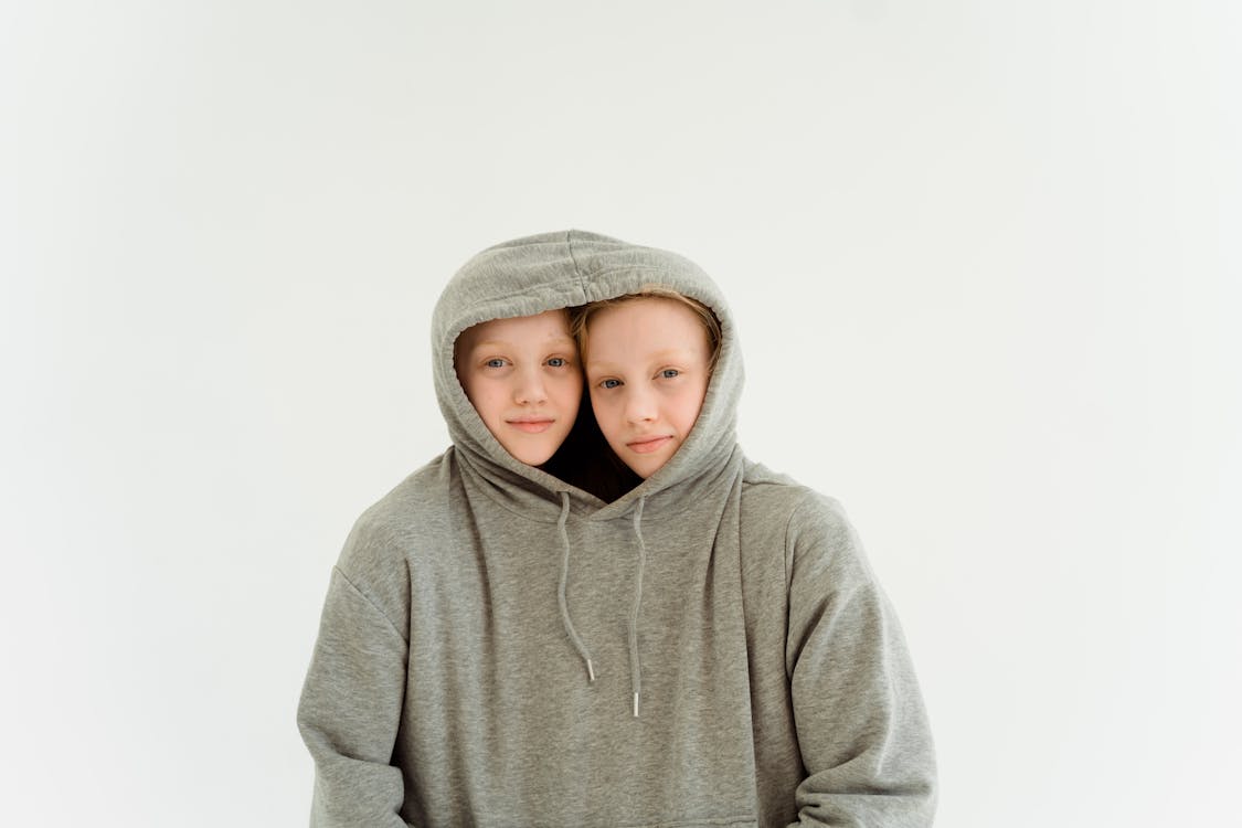 Two Young Girls Together in One Gray Hoodie Sweater