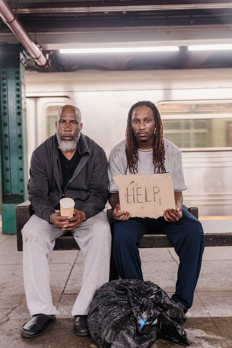 Men Sitting With Placard At Subway Station