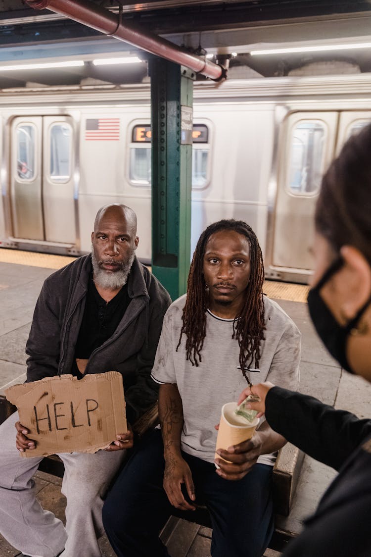 Woman Giving Money To Men On A Subway Station 