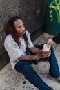 A Person Giving Alms to a Man Sitting on the Floor Holding a Cup
