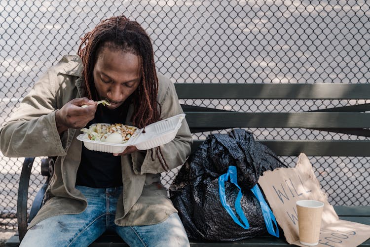 Man Sitting On Bench And Eating