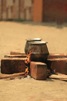 Traditional outdoor cooking with pots on a brick fire pit, showcasing rustic culinary methods.