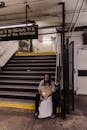 Man in White Crew Neck T-shirt Sitting on Black and Yellow Staircase