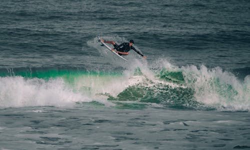 Photo of a Man in a Black Wetsuit Surfing on the Ocean Waves