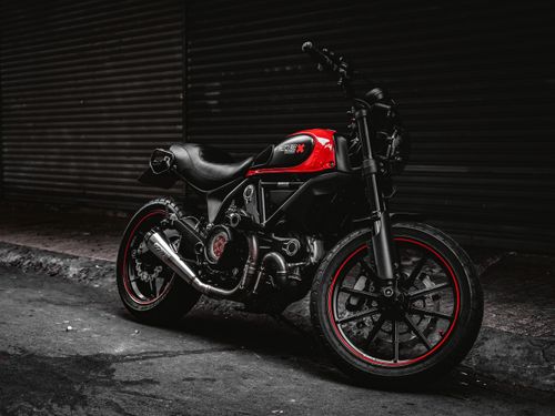 Free Moody shot of a red Ducati motorcycle parked on a street, exuding style and strength. Stock Photo