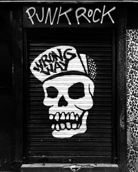 Black and white street art of a skull with cap in Madrid, emits punk vibe.