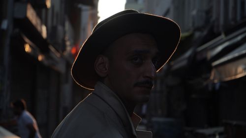 Free Silhouette of a man in a hat with dramatic backlighting on a city street at sunset. Stock Photo