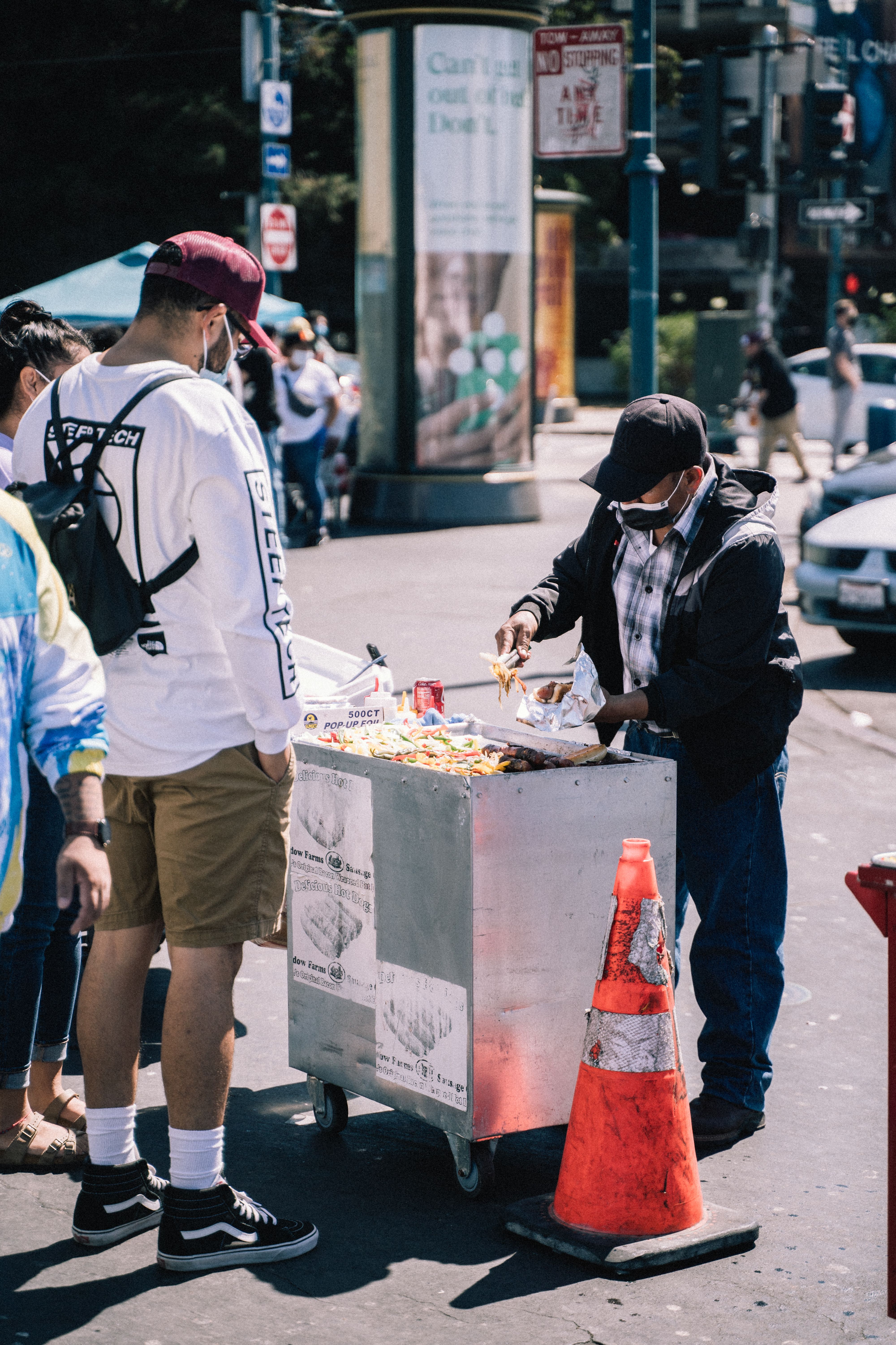 man in white shirt and black hat standing in front of food stall