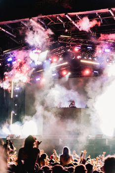 Vibrant DJ performance at a music festival with an enthusiastic crowd and dynamic stage lighting.