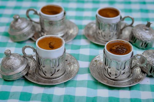 Free Close-up of four ornate Turkish coffee cups and saucers on a green checkered tablecloth. Stock Photo