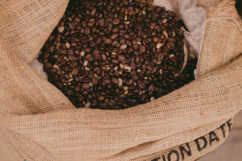 Free Close-up of roasted coffee beans in a burlap sack, showcasing texture and richness. Stock Photo