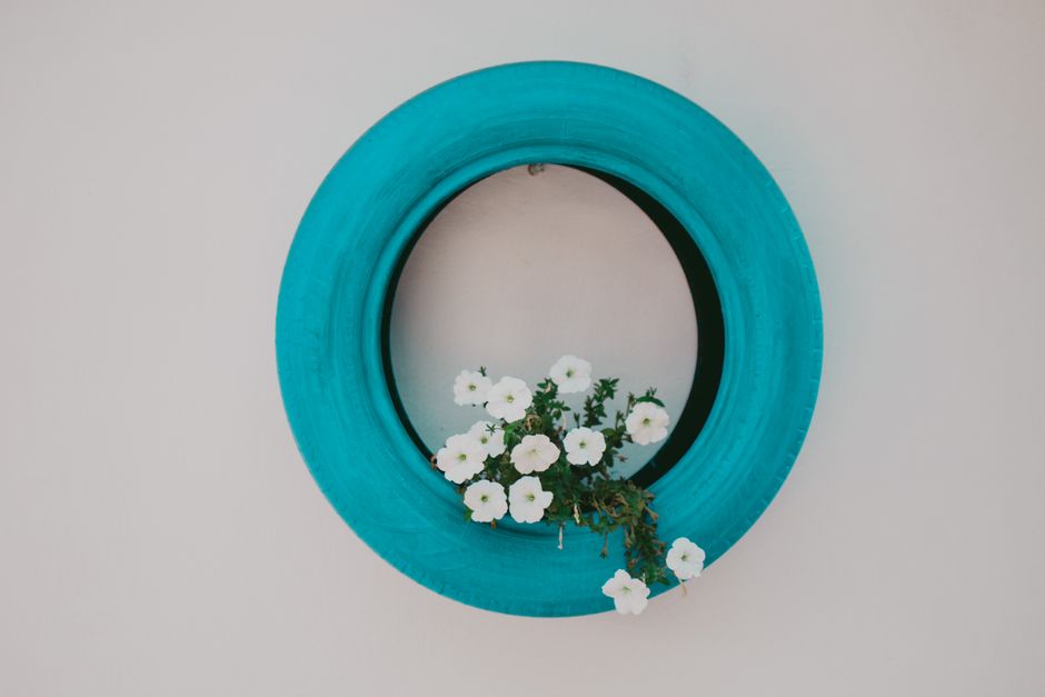 Repurposed Tire Planter DIY home decor project — Unique wall decoration featuring blue tire with white flowers for creative home decor.