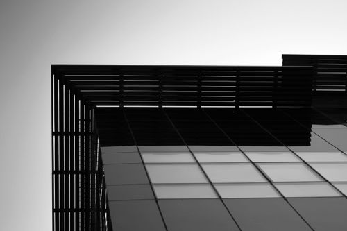 Free Low angle shot of a modern building exterior with sleek, urban design in black and white. Stock Photo