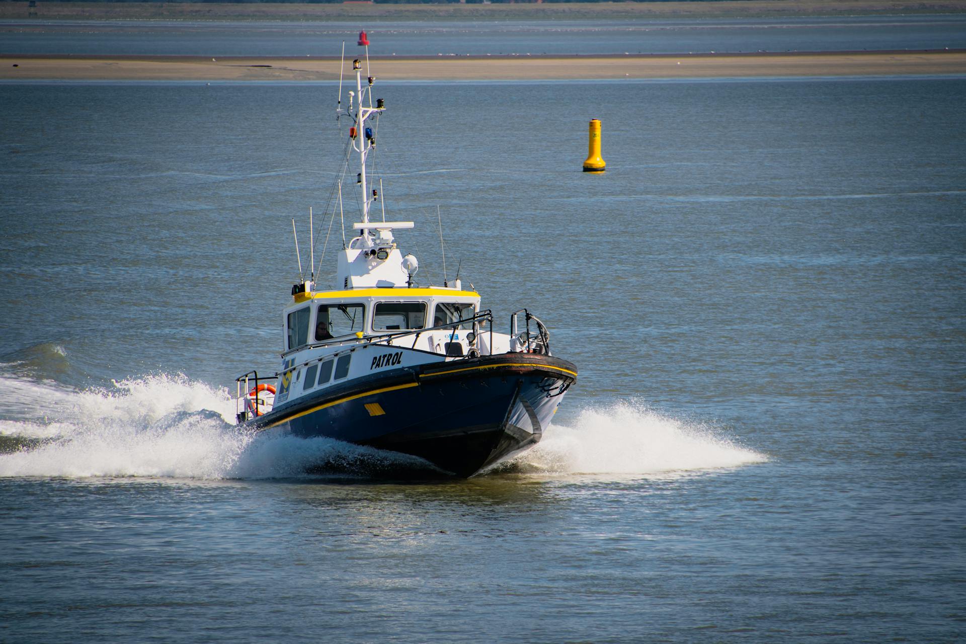 Patrol boat speeding through open sea water, creating splashes as it navigates.