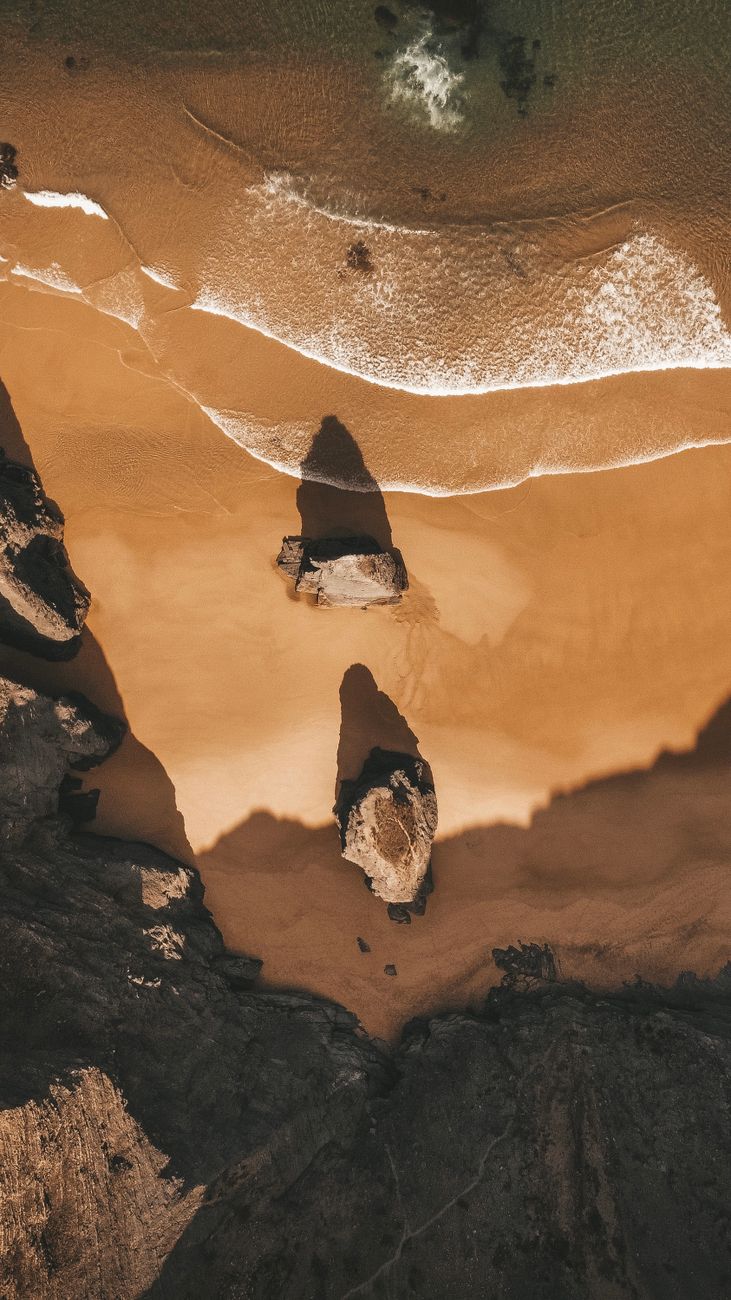 Stunning aerial view of Portuguese beach with waves and unique rock formations.