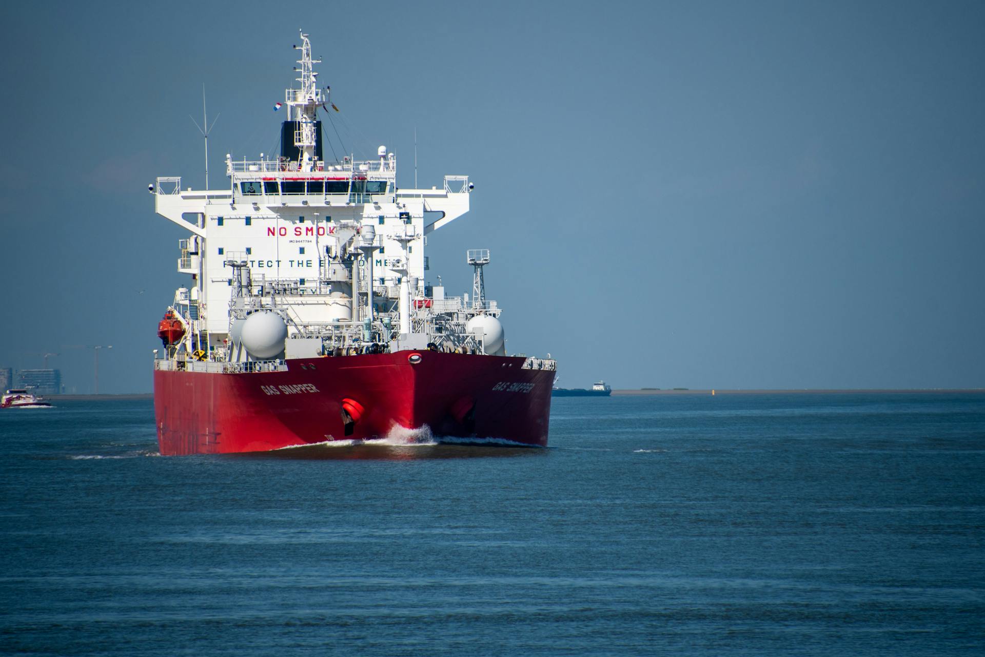 A red cargo ship navigates calm blue ocean waters, showcasing maritime transportation.