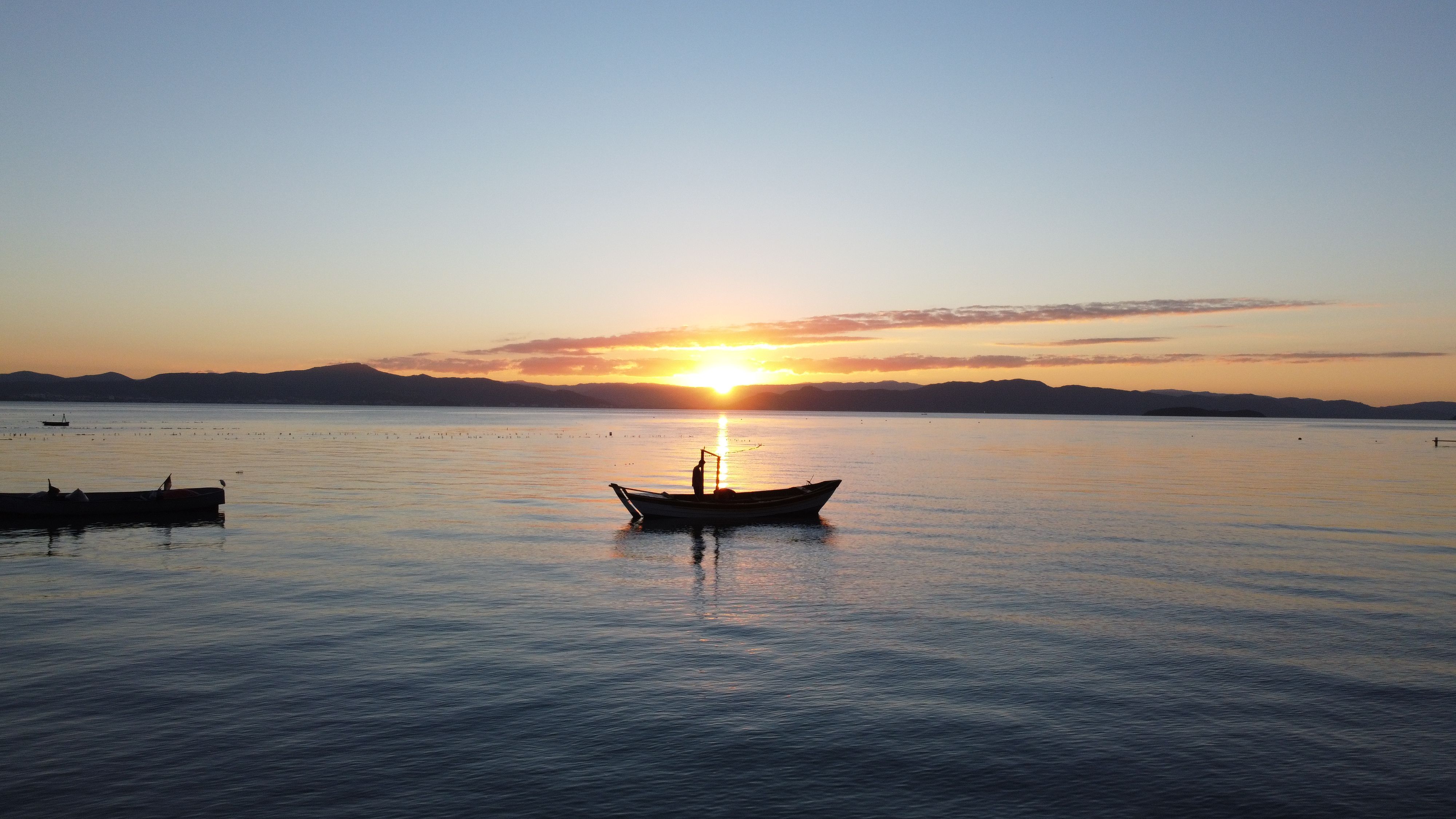 Late-summer beach at dusk with fishing boats and calm sea