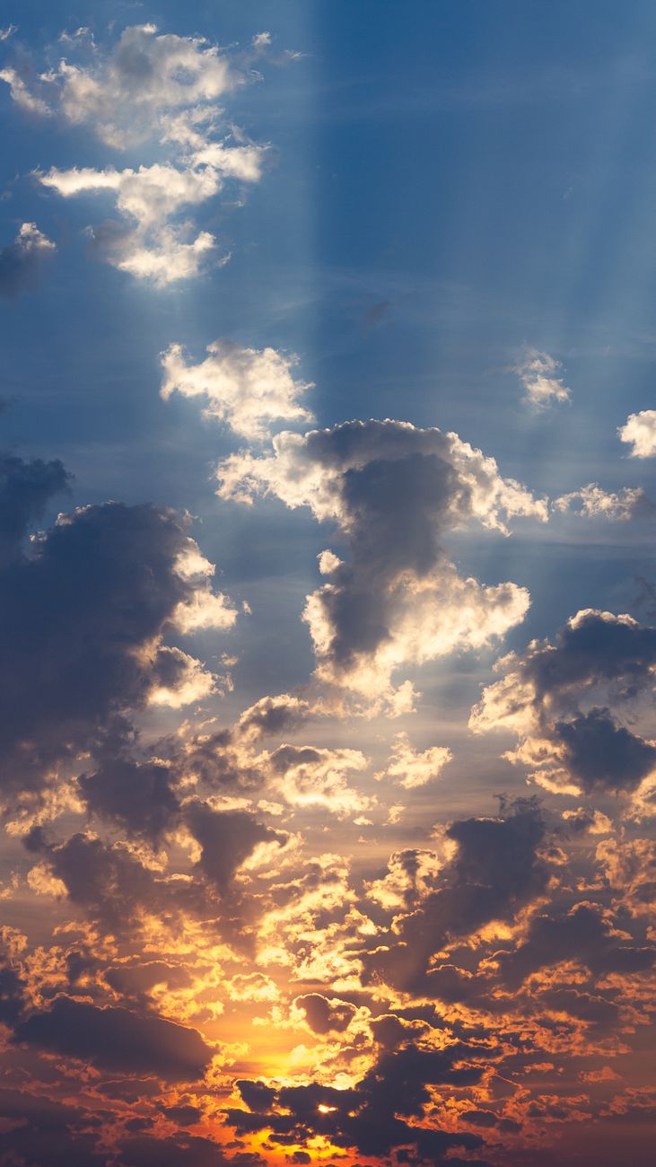 Dramatic sky with sunbeams streaming through clouds at sunset.