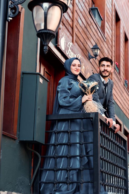 Free A joyful couple in wedding attire standing on a balcony, showcasing love and elegance. Stock Photo