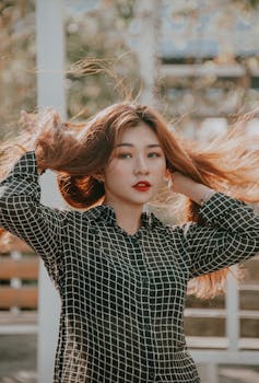 一位时尚的年轻女子留着飘逸的长发，在户外摆着姿势，散发着美丽与时尚的气息