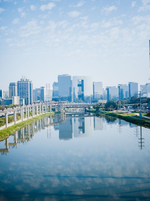 Free Reflective urban skyline by the river on a clear day, showcasing modern architecture. Stock Photo