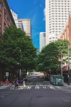 City street scene with pedestrians crossing under a clear blue sky.