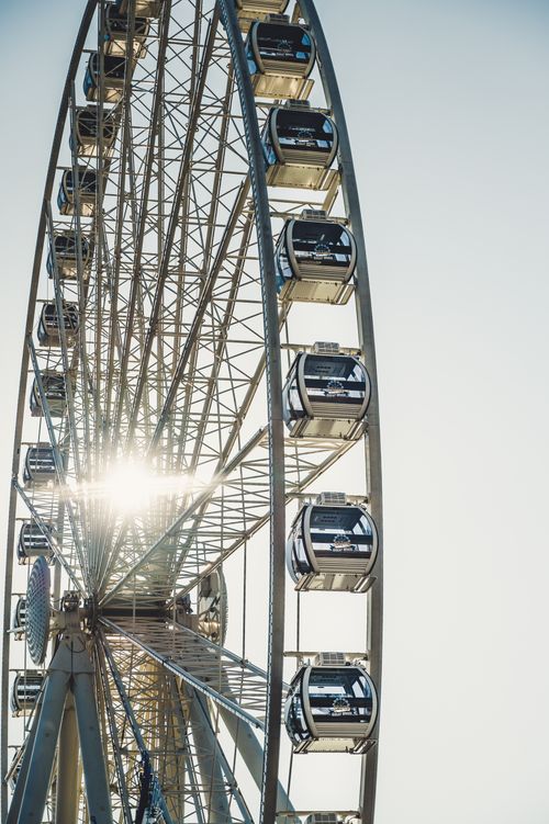 Free Beautiful Ferris wheel structure with sun gleaming through at an amusement park. Stock Photo