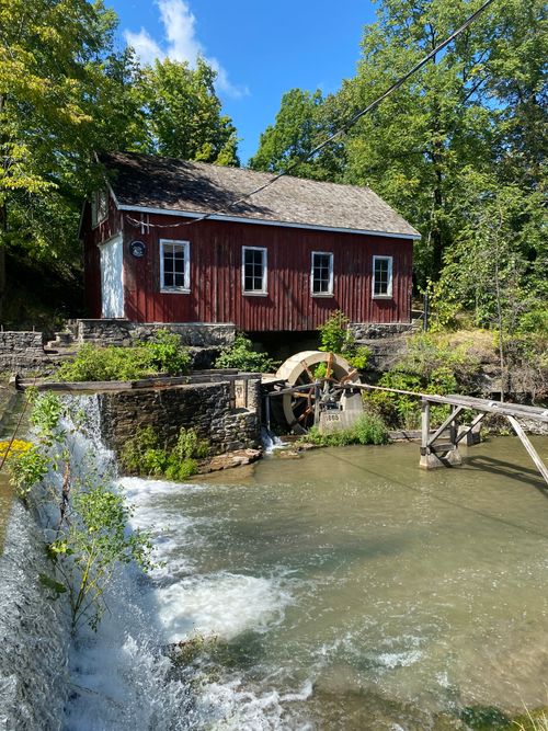 Free A charming red watermill along a peaceful river on a sunny summer day. Stock Photo