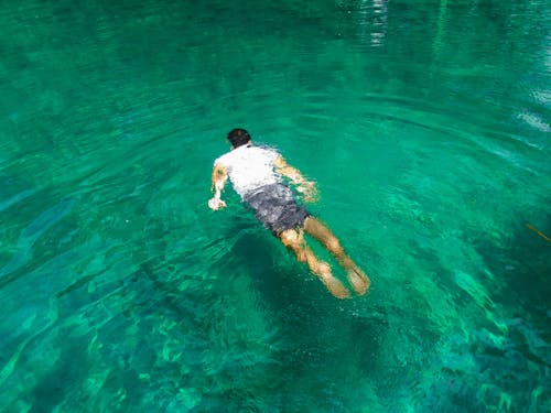맑은 물에서 수영하는 남자의 사진