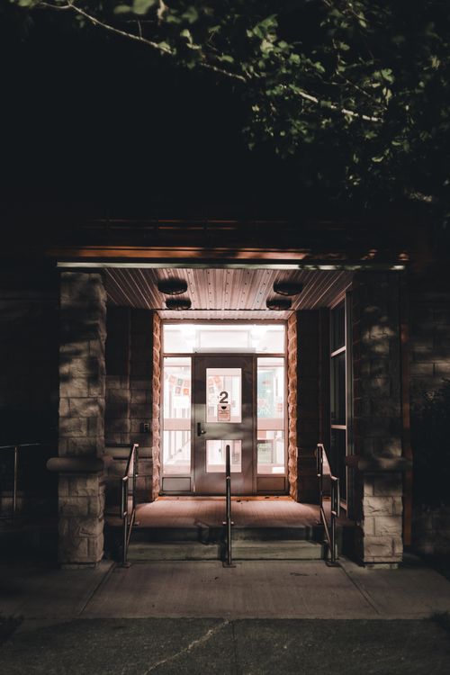 Free A dimly lit entrance with glass doors and handrails at night, showcasing architectural structure. Stock Photo