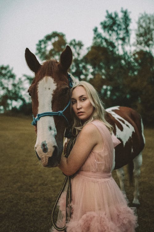 Woman in Pink Dress Standing Beside a Horse