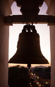 Silhouette of a historic bell at sunset in León, Nicaragua, blending architecture with serene skies.