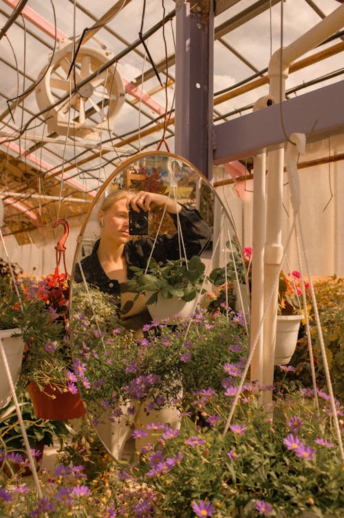 Woman in White Shirt Standing Near Green Plants