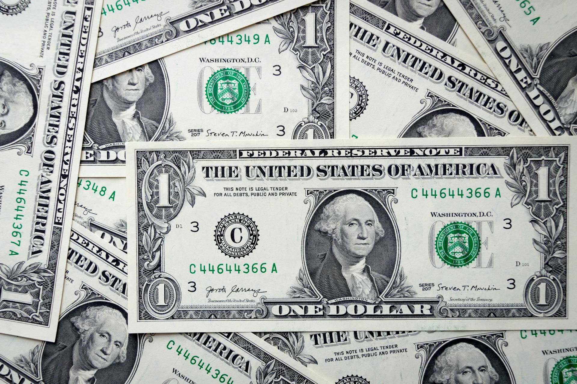 Detailed close-up of multiple one dollar bills showcasing U.S. currency design.