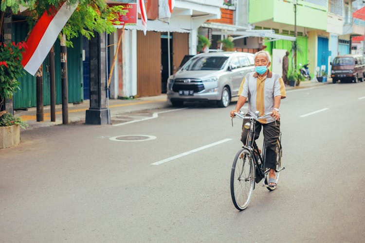 Elderly Man Riding A Bike On The Road